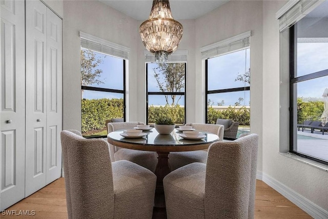 dining space with light wood-style flooring, baseboards, and a chandelier