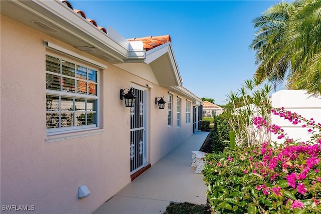 exterior space with stucco siding, a tiled roof, and fence