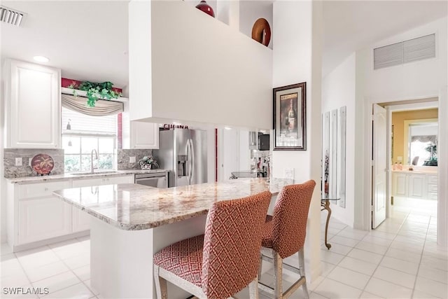 kitchen featuring a sink, visible vents, appliances with stainless steel finishes, and a breakfast bar area