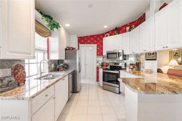 kitchen with a sink, stainless steel appliances, white cabinets, and wallpapered walls