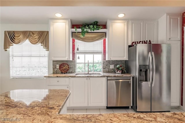 kitchen featuring white cabinetry, backsplash, appliances with stainless steel finishes, and a sink