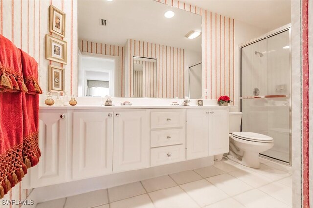 bathroom with tile patterned floors, toilet, a sink, a shower stall, and wallpapered walls