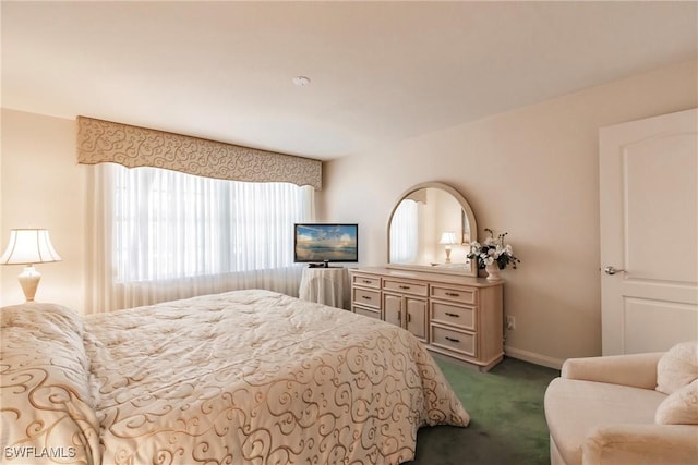 bedroom with dark carpet and baseboards