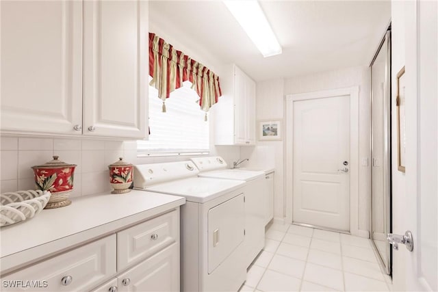 laundry area featuring light tile patterned floors, cabinet space, and washing machine and dryer