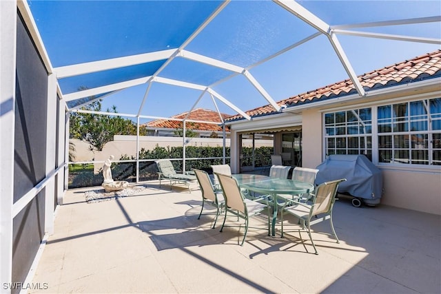 view of patio with area for grilling, glass enclosure, and outdoor dining area