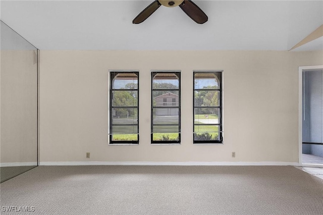 carpeted empty room featuring a ceiling fan and baseboards