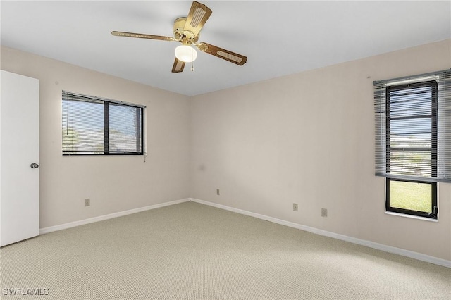 unfurnished room featuring baseboards, light colored carpet, and ceiling fan