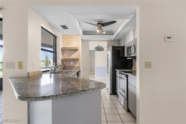 kitchen featuring visible vents, a peninsula, a sink, stainless steel appliances, and a raised ceiling