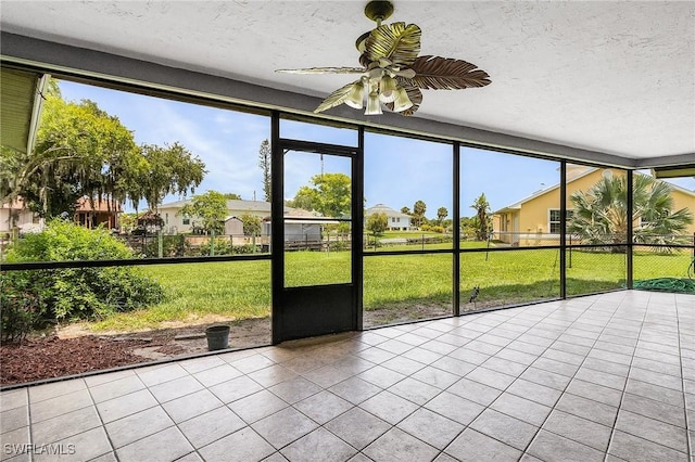 unfurnished sunroom featuring a residential view and a ceiling fan