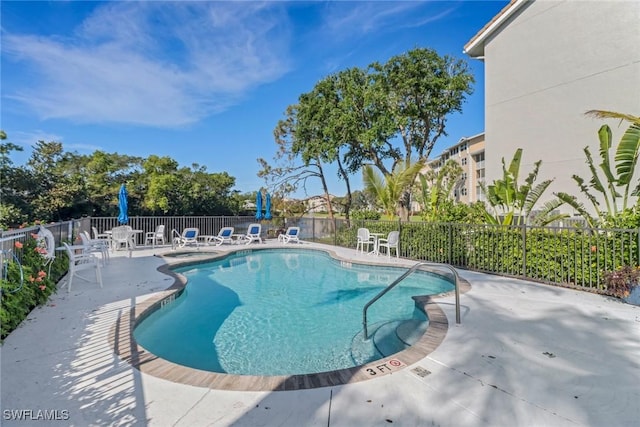 community pool with a patio and fence