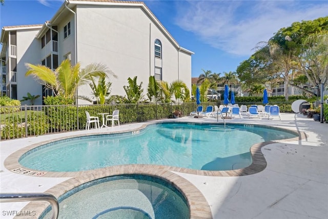 community pool with a patio area, a community hot tub, and fence