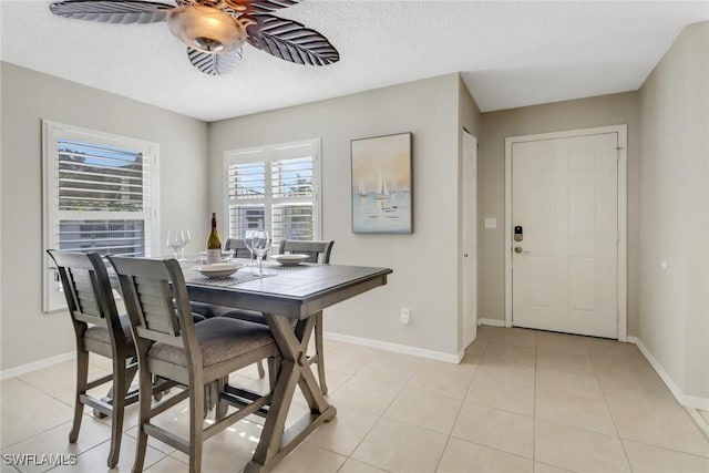 dining space with light tile patterned floors, baseboards, a textured ceiling, and ceiling fan