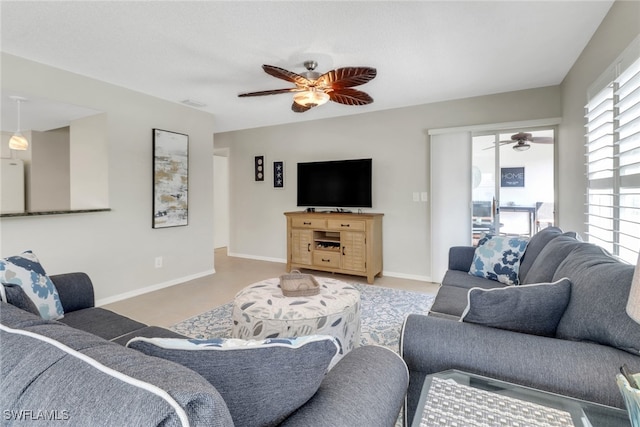 living area with baseboards and ceiling fan