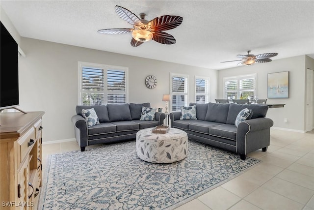 living area with light tile patterned floors, baseboards, a textured ceiling, and a ceiling fan