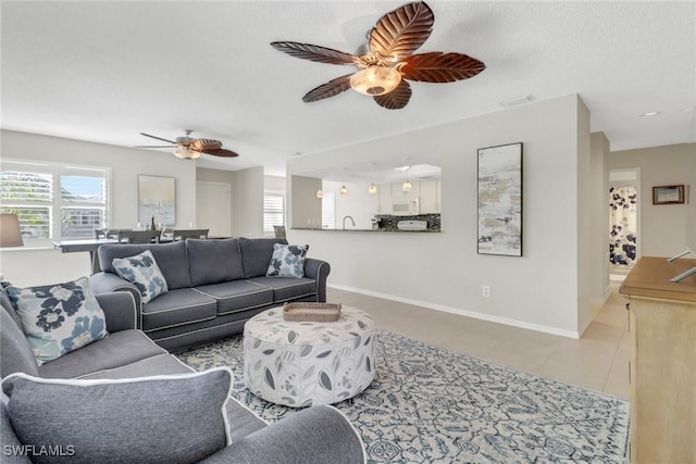 living area with tile patterned floors, visible vents, baseboards, and a ceiling fan