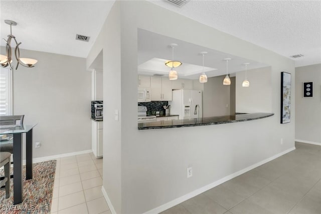 kitchen with visible vents, a tray ceiling, tasteful backsplash, a textured ceiling, and white appliances