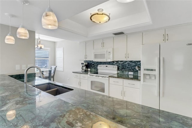 kitchen with decorative backsplash, white appliances, a tray ceiling, and a sink