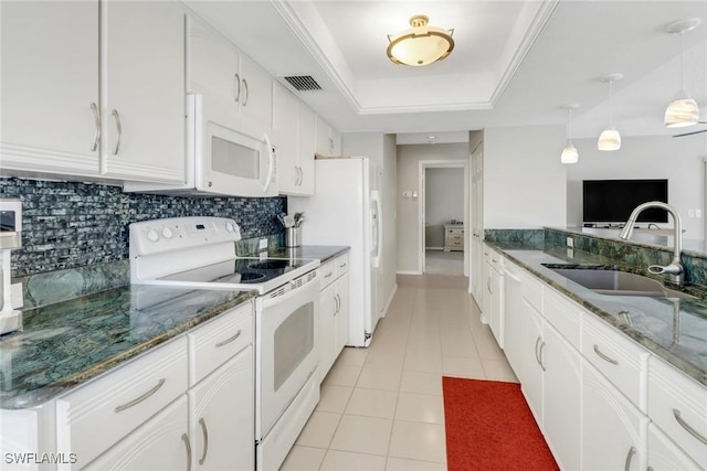 kitchen with visible vents, a sink, a tray ceiling, backsplash, and white appliances