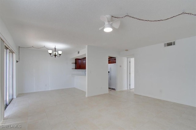 empty room featuring visible vents, ceiling fan with notable chandelier, and a textured ceiling