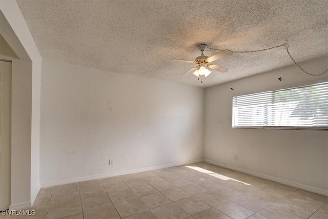 tiled spare room featuring a ceiling fan, baseboards, and a textured ceiling