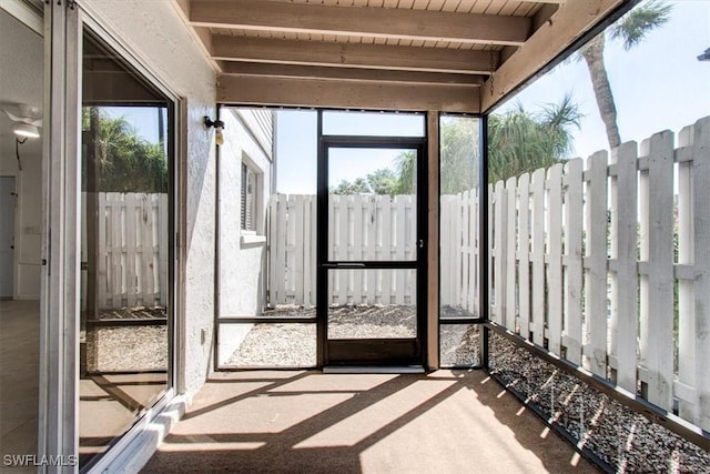 unfurnished sunroom with beam ceiling, a healthy amount of sunlight, and wooden ceiling