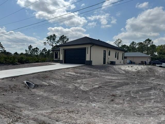 view of side of home with concrete driveway, a garage, and stucco siding