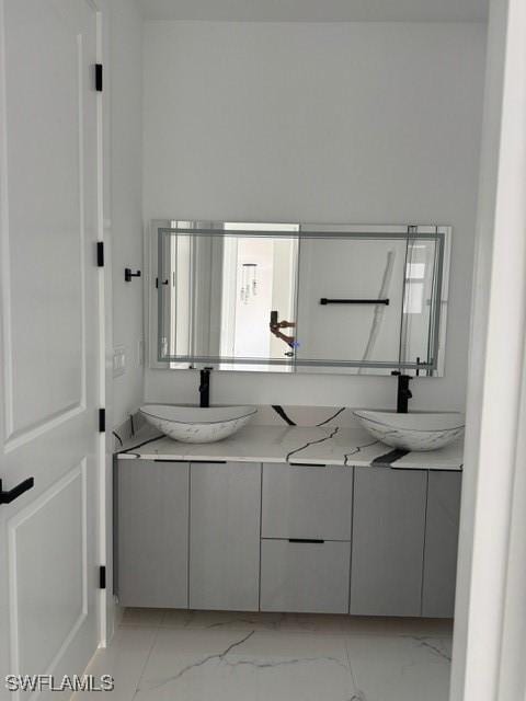 bathroom with double vanity, marble finish floor, and a sink