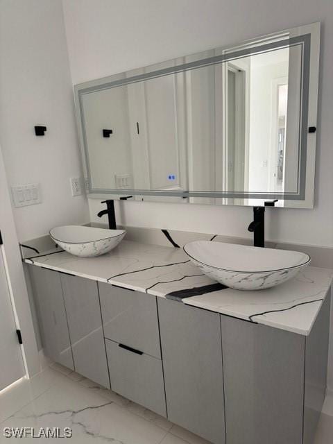 bathroom featuring double vanity, marble finish floor, and a sink