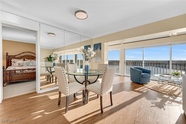 dining space with plenty of natural light, wood finished floors, and ornamental molding