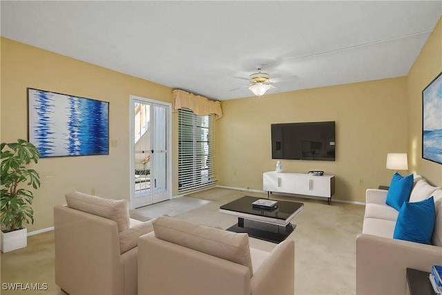 living room featuring light carpet, baseboards, and a ceiling fan