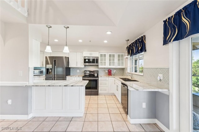 kitchen featuring appliances with stainless steel finishes, light stone countertops, a peninsula, and a sink