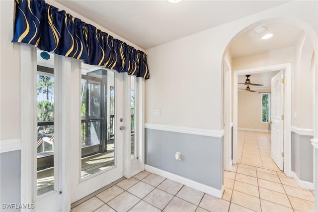 interior space featuring tile patterned floors, arched walkways, baseboards, and a wealth of natural light