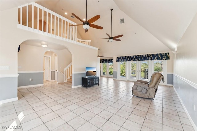 unfurnished living room with visible vents, arched walkways, light tile patterned floors, baseboards, and stairs