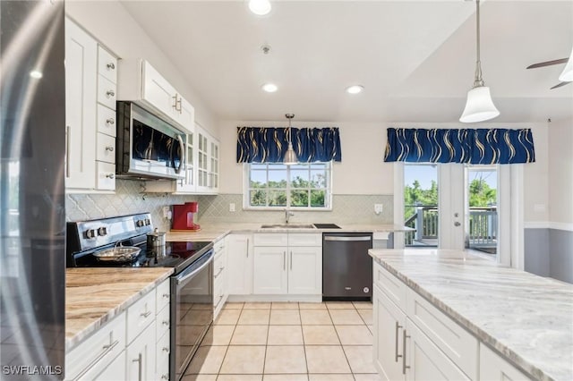 kitchen featuring light tile patterned floors, decorative backsplash, appliances with stainless steel finishes, white cabinetry, and a sink