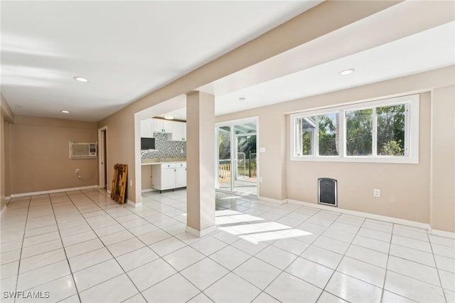 empty room with a wall unit AC, light tile patterned floors, recessed lighting, and baseboards