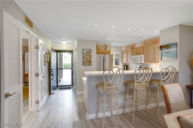 kitchen featuring white microwave, visible vents, a peninsula, freestanding refrigerator, and light countertops