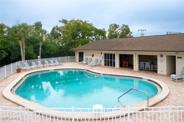 community pool with a patio area and fence