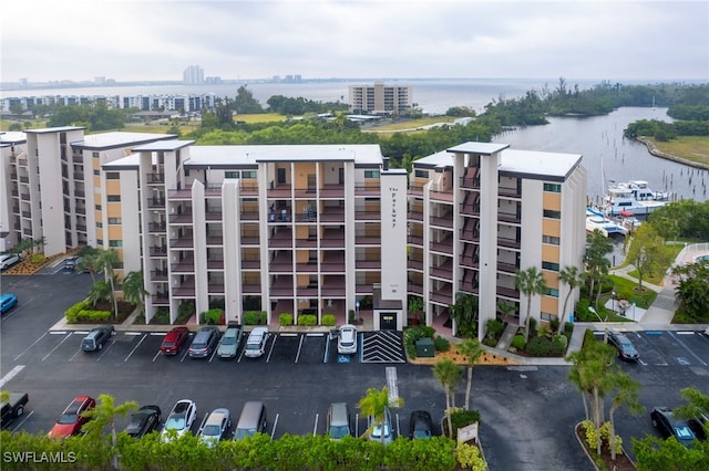 view of building exterior with a city view, a water view, and uncovered parking