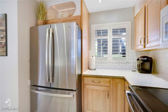 kitchen with light countertops, backsplash, light brown cabinets, and freestanding refrigerator