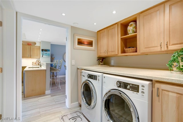 clothes washing area featuring cabinet space, recessed lighting, washer and dryer, and a sink