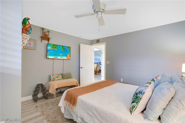 bedroom featuring baseboards, wood finished floors, visible vents, and ceiling fan