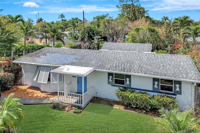 single story home featuring stucco siding, a porch, a shingled roof, and a front yard