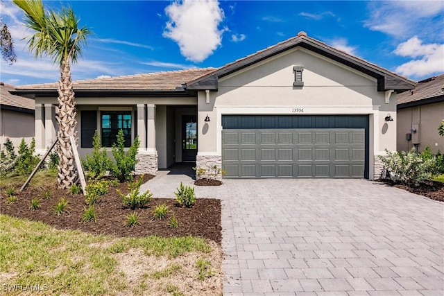 ranch-style house featuring stone siding, stucco siding, decorative driveway, and an attached garage