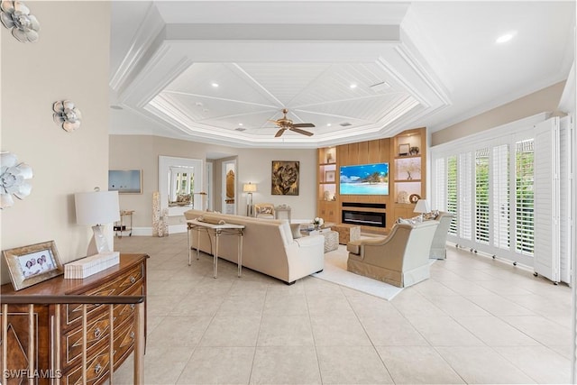 living room featuring light tile patterned floors, a ceiling fan, baseboards, a glass covered fireplace, and crown molding