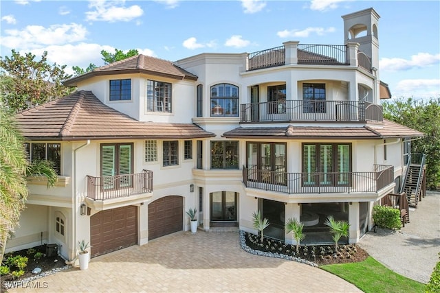 view of front facade with stucco siding, decorative driveway, a garage, and a tile roof