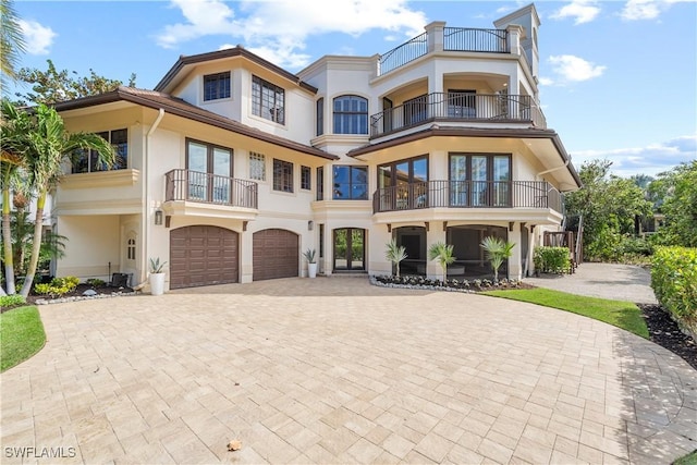 view of front of home featuring stucco siding, an attached garage, driveway, and french doors