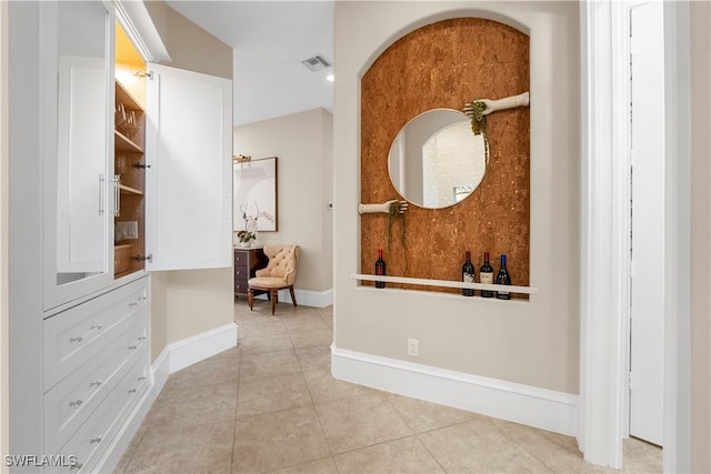 hall featuring light tile patterned floors, visible vents, and baseboards