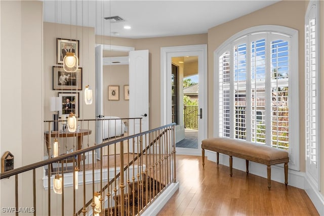 hallway with wood finished floors, recessed lighting, an upstairs landing, and visible vents