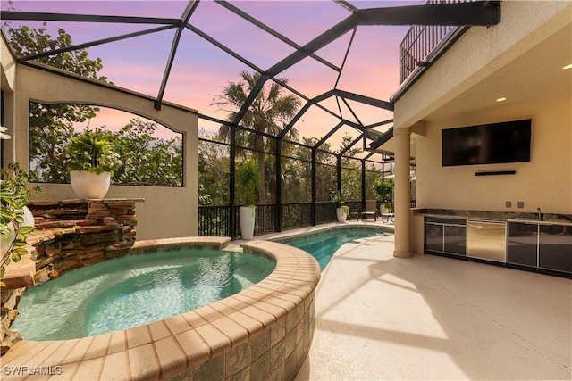 pool with glass enclosure, a patio, an in ground hot tub, and exterior kitchen