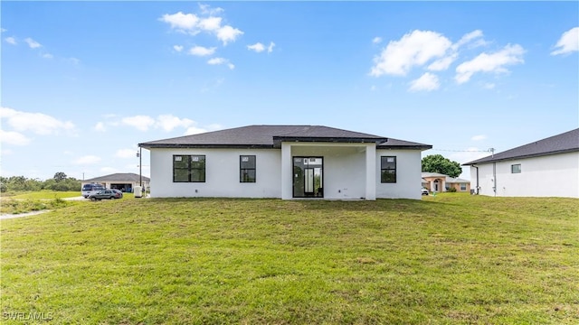 rear view of house featuring stucco siding and a yard